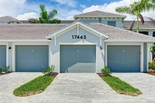 17445 Opal Sand Dr Unit 104, Venice, FL 34293 - view of front of house with community garages, a tiled roof, and stucco siding