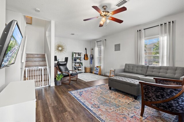 living room with dark wood-type flooring and ceiling fan