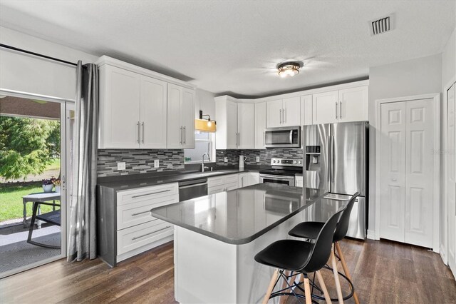 kitchen featuring dark hardwood / wood-style flooring, decorative backsplash, appliances with stainless steel finishes, white cabinets, and sink