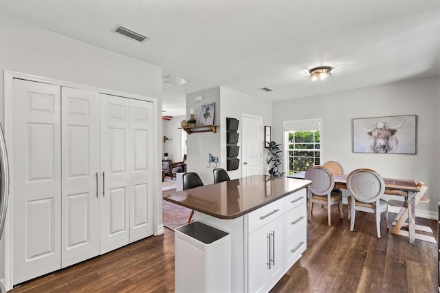 kitchen with white cabinets, dark hardwood / wood-style flooring, a textured ceiling, and a center island