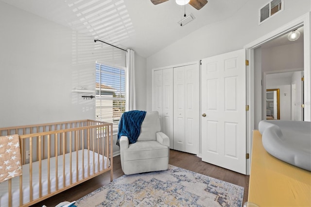 bedroom with ceiling fan, lofted ceiling, a crib, hardwood / wood-style flooring, and a closet