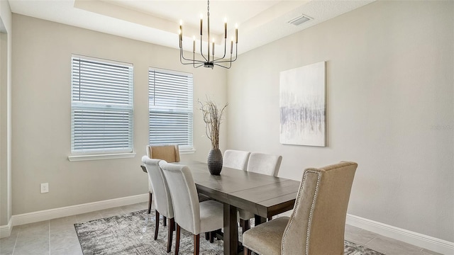 dining room with a raised ceiling, an inviting chandelier, and light tile patterned floors