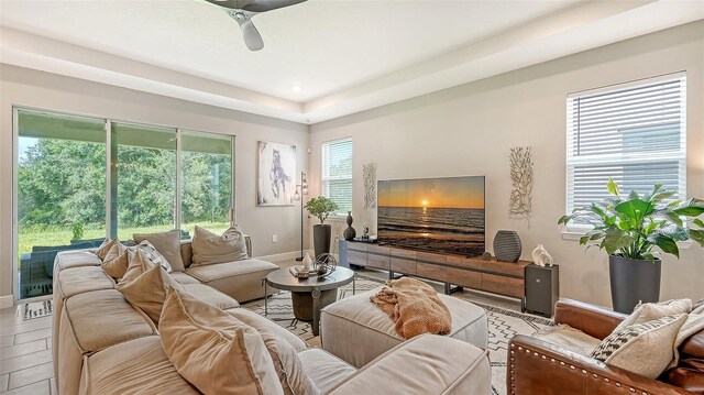 living room with ceiling fan and a tray ceiling