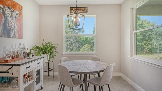 tiled dining space featuring a chandelier and a healthy amount of sunlight