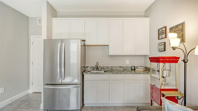 kitchen featuring light tile patterned floors, sink, white cabinets, and stainless steel fridge