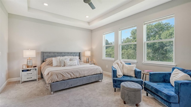 carpeted bedroom featuring ceiling fan and a raised ceiling