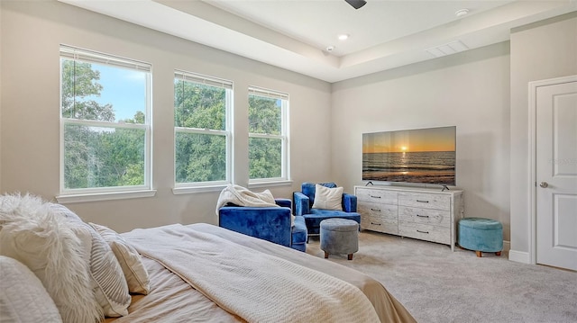 carpeted bedroom featuring ceiling fan, a raised ceiling, and multiple windows