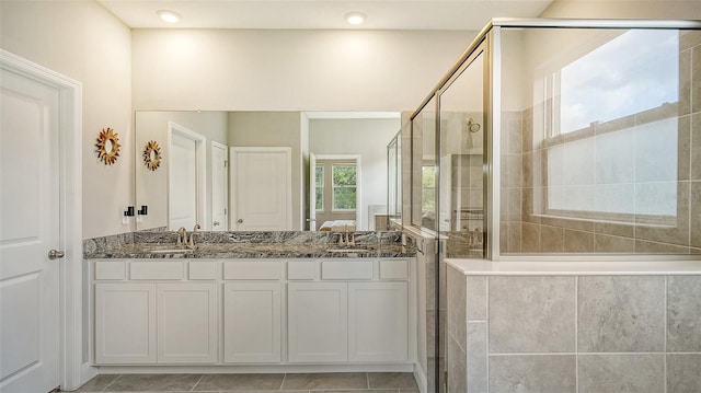 bathroom featuring double sink vanity, tile patterned floors, and a shower with shower door