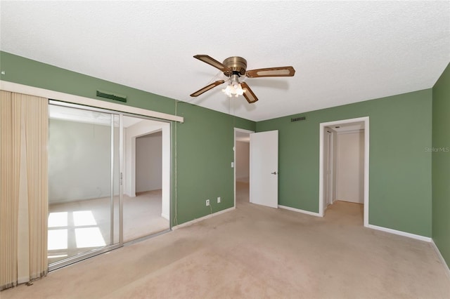 unfurnished bedroom with ceiling fan, light carpet, a textured ceiling, and a closet