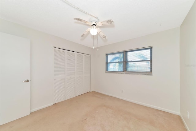 unfurnished bedroom featuring light colored carpet, ceiling fan, and a closet