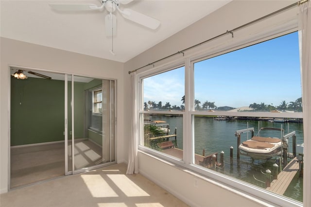 sunroom / solarium featuring ceiling fan and a water view