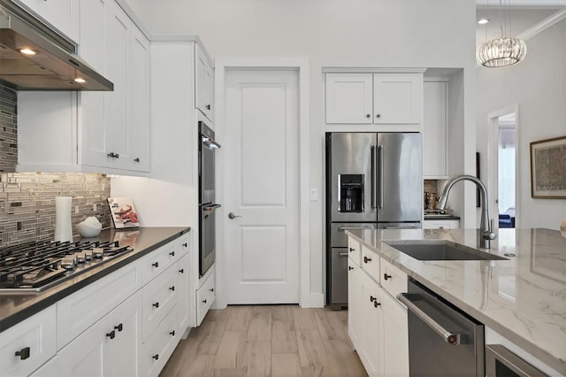 kitchen featuring appliances with stainless steel finishes, tasteful backsplash, sink, white cabinetry, and light wood-type flooring