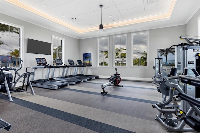 workout area featuring a raised ceiling and crown molding