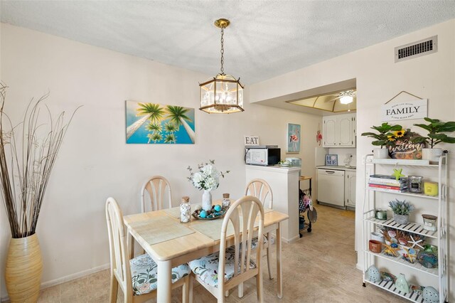 dining area featuring ceiling fan with notable chandelier and a textured ceiling