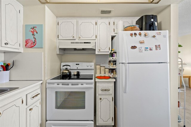 kitchen featuring range, a textured ceiling, tile patterned floors, white cabinetry, and white fridge