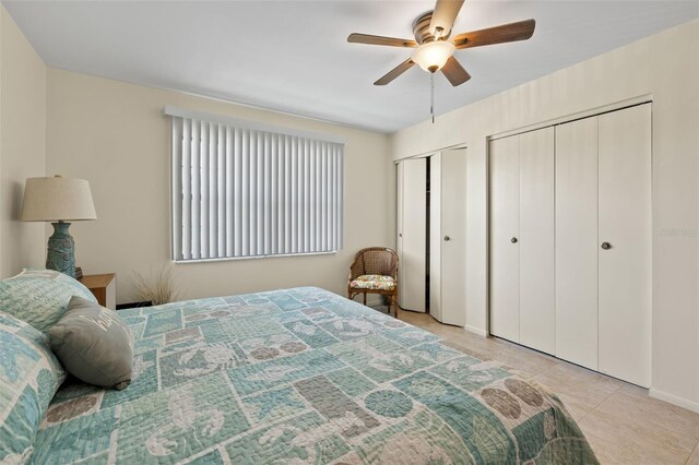 bedroom with light tile patterned flooring, multiple closets, and ceiling fan