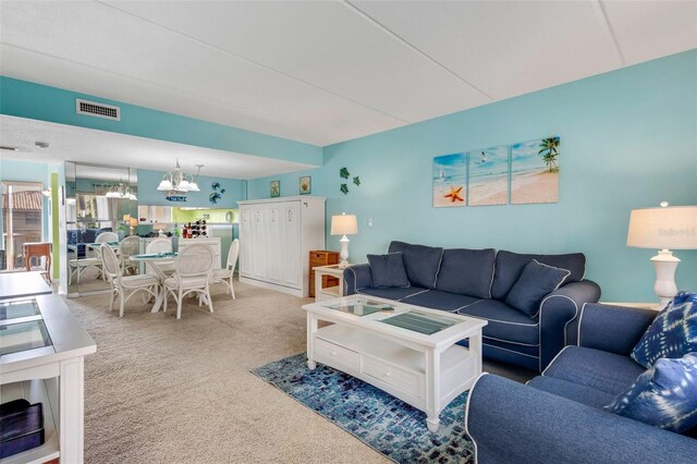 living room featuring light carpet and an inviting chandelier