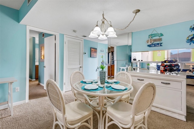 dining area with a textured ceiling, light carpet, and an inviting chandelier