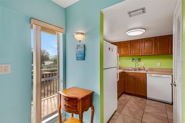 kitchen featuring light tile patterned flooring, white appliances, and sink