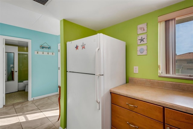 kitchen with white fridge and light tile patterned floors