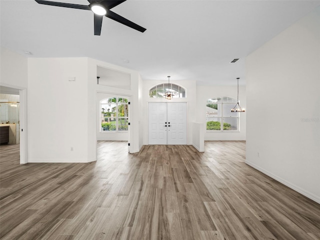 foyer featuring ceiling fan with notable chandelier and wood-type flooring