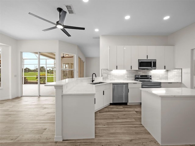 kitchen with tasteful backsplash, sink, appliances with stainless steel finishes, and light wood-type flooring