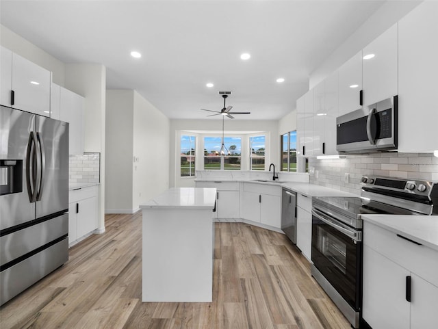 kitchen featuring white cabinetry, light hardwood / wood-style flooring, tasteful backsplash, a center island, and stainless steel appliances