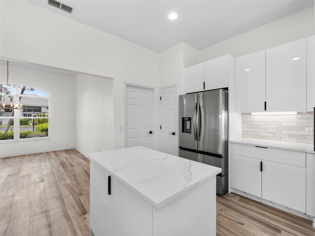 kitchen featuring light hardwood / wood-style flooring, tasteful backsplash, light stone countertops, stainless steel fridge with ice dispenser, and white cabinetry