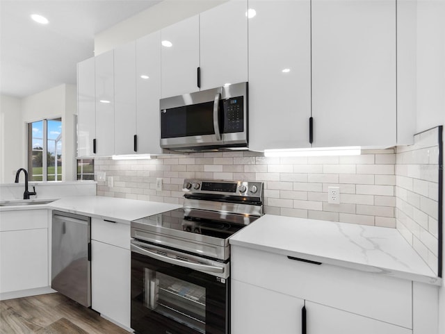 kitchen featuring sink, appliances with stainless steel finishes, white cabinets, and light hardwood / wood-style floors