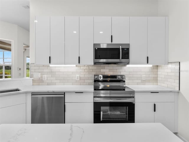 kitchen with white cabinets, backsplash, and appliances with stainless steel finishes