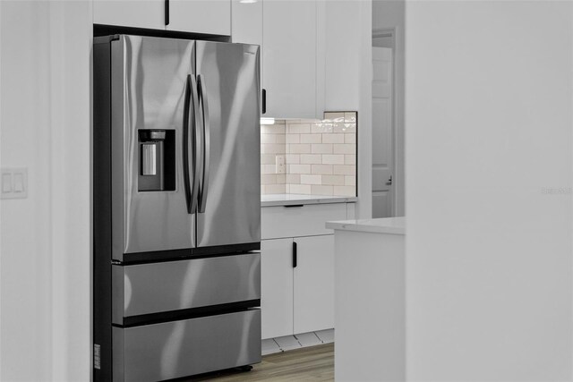 kitchen with white cabinetry, decorative backsplash, light wood-type flooring, and stainless steel fridge with ice dispenser