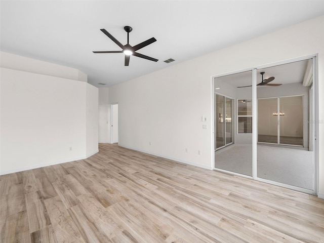 empty room featuring ceiling fan with notable chandelier and light wood-type flooring