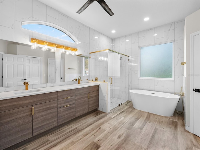 bathroom with hardwood / wood-style flooring, vanity, shower with separate bathtub, and tile walls