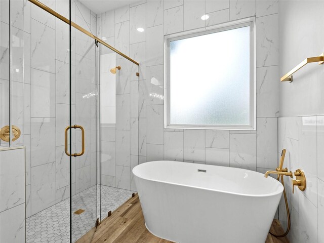 bathroom featuring tile walls, hardwood / wood-style flooring, and shower with separate bathtub