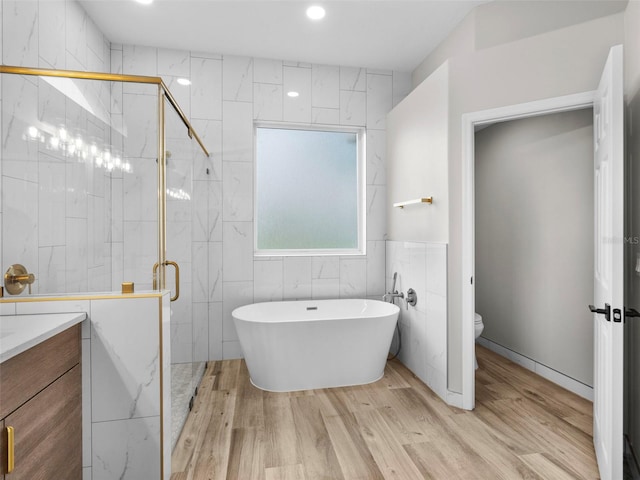 full bathroom featuring tile walls, vanity, wood-type flooring, shower with separate bathtub, and toilet