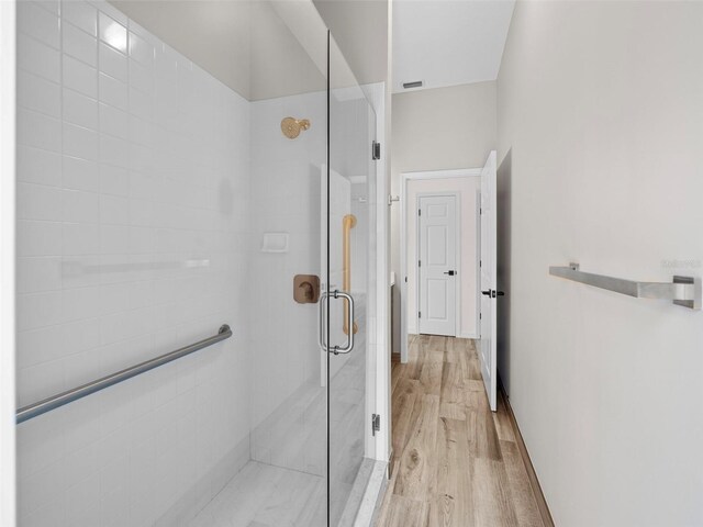 bathroom with hardwood / wood-style floors and an enclosed shower