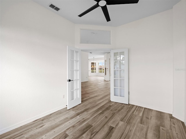 unfurnished room with ceiling fan, light hardwood / wood-style floors, and french doors