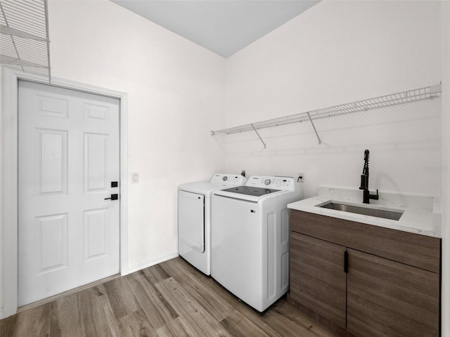 laundry area featuring washing machine and clothes dryer, light wood-type flooring, and sink