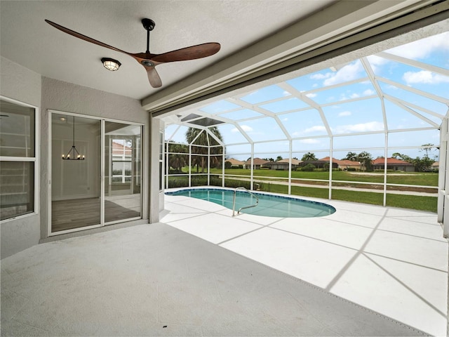 view of swimming pool with a patio, ceiling fan, a lawn, and glass enclosure