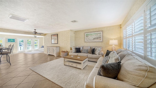 living room with light tile patterned floors, french doors, a textured ceiling, and ceiling fan