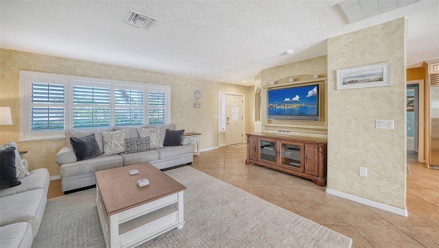 living room with a textured ceiling and light tile patterned flooring