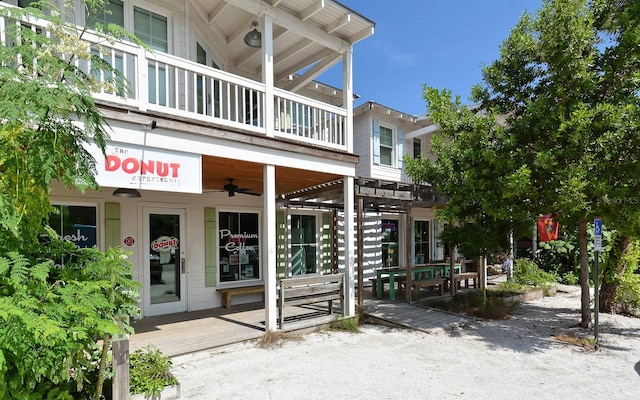 back of property with a balcony, ceiling fan, and a pergola