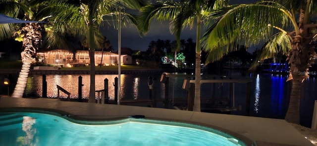 pool at twilight featuring a water view