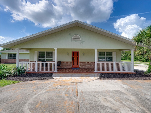 view of front of property with stucco siding, a porch, and brick siding