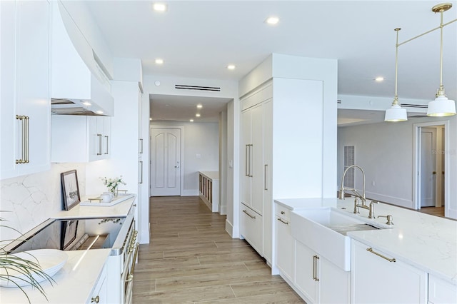 kitchen featuring sink, light stone counters, decorative backsplash, white cabinets, and decorative light fixtures