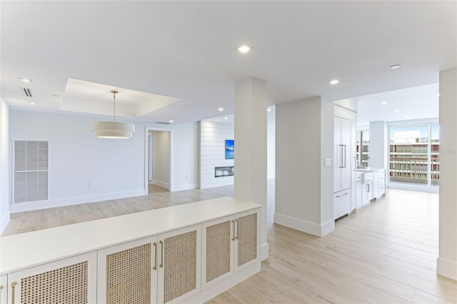 corridor featuring a raised ceiling and light hardwood / wood-style floors