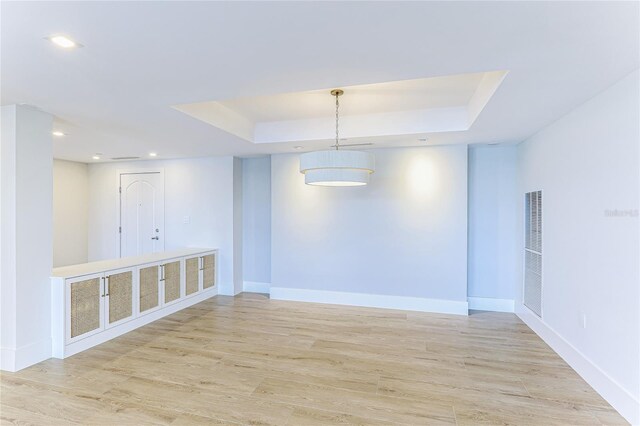 unfurnished room featuring light hardwood / wood-style flooring and a tray ceiling