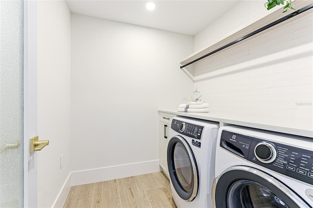 laundry area featuring cabinets, washing machine and clothes dryer, and light hardwood / wood-style flooring