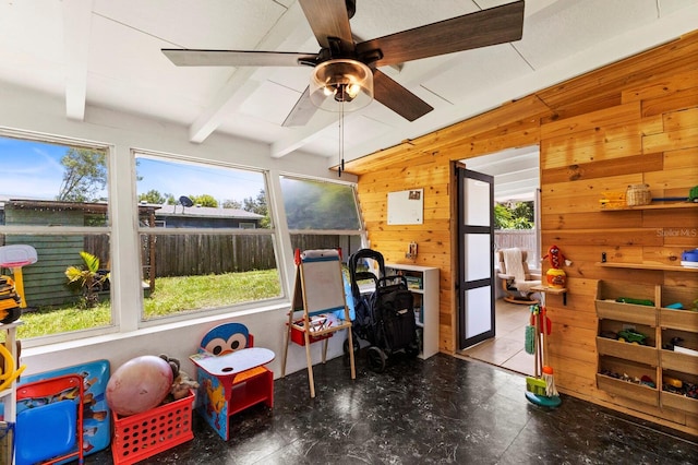 recreation room featuring beam ceiling, wood walls, and plenty of natural light