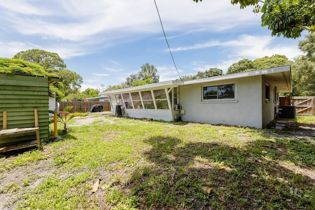 back of property with a yard, central AC, and a sunroom